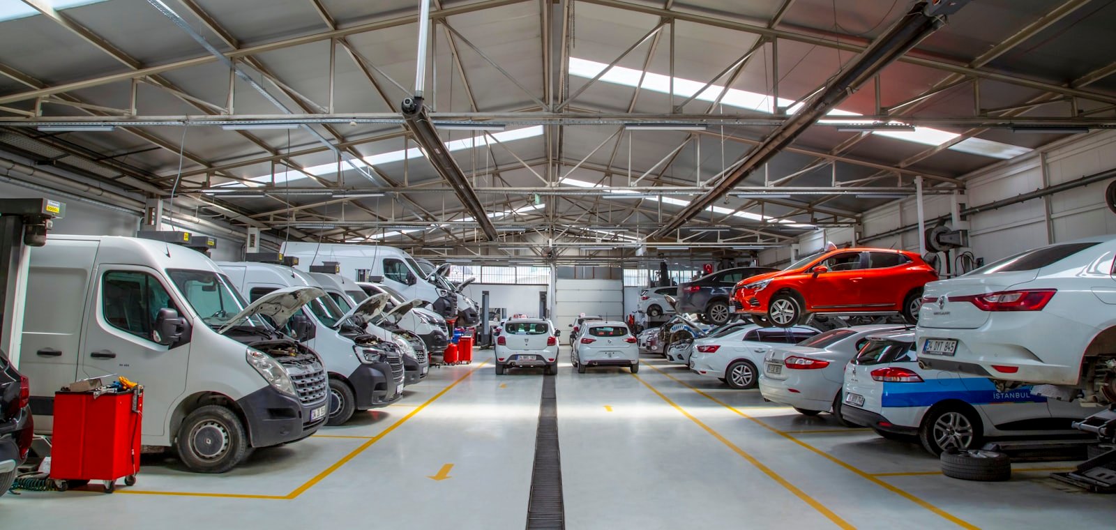 Blick durch die Werkstatthalle, Transporter und Pkw an den Arbeitsplätzen